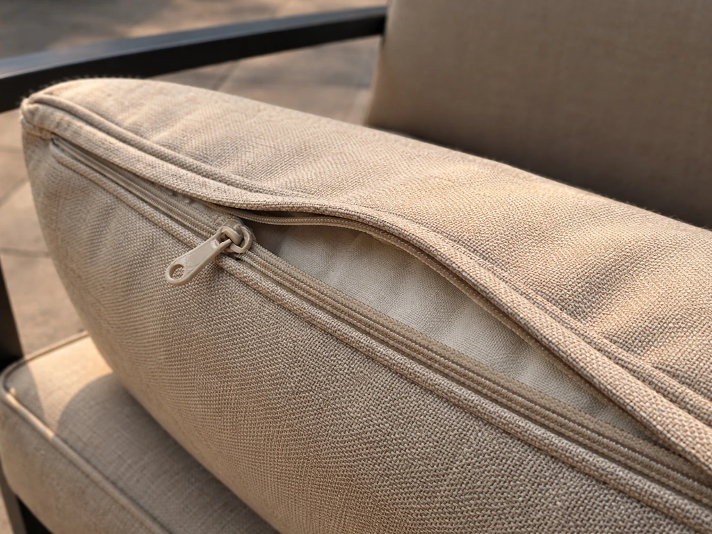 Close-up of an outdoor cushion’s fabric weave and zipper seam with subtle sunlight fade gradient.