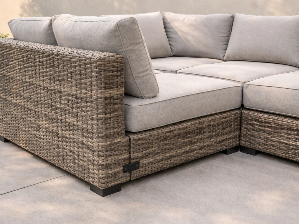 Close view of a modular resin-wicker outdoor sofa showing connector joints and aluminum frame outdoors.